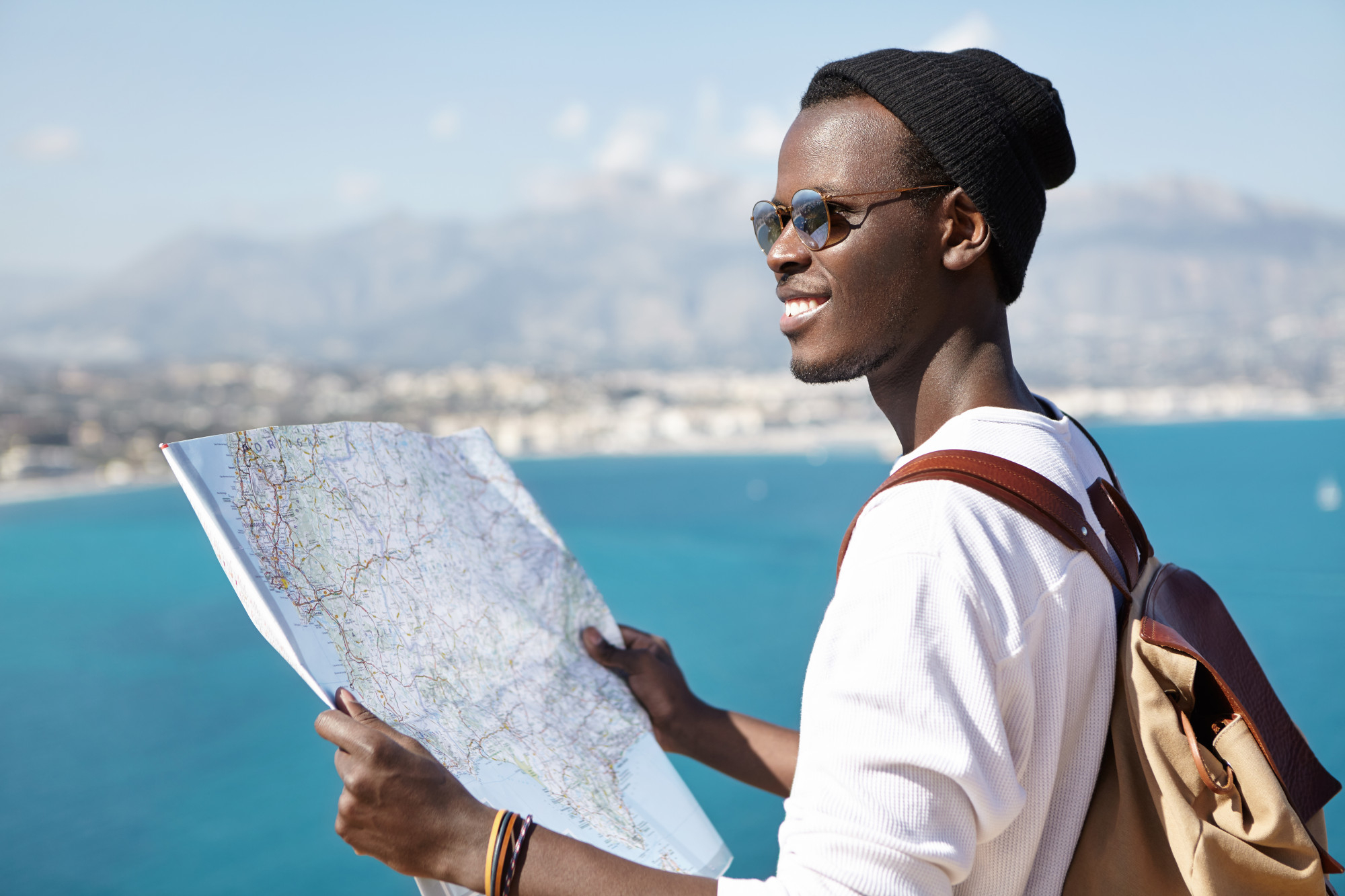 what-beautiful-landscape-happy-excited-afro-american-backpacker-using-paper-map-while-standing-viewing-point-high-blue-sea-studying-surroundings-during-his-trip-travel-adventure